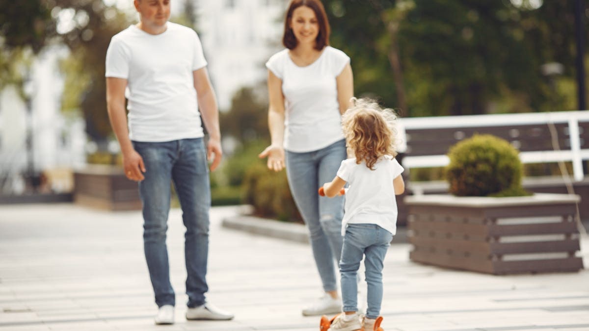 Happy family spending quality time together outdoors, with a child riding a skateboard.